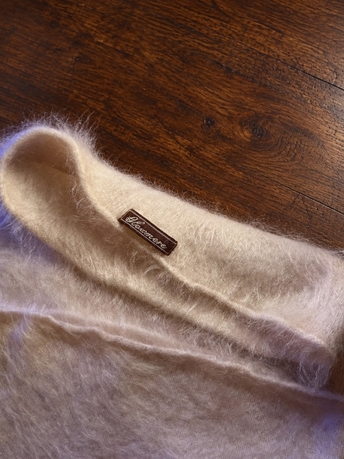 Ivory brushed knitwear with Glowmere woven label on warm wood
